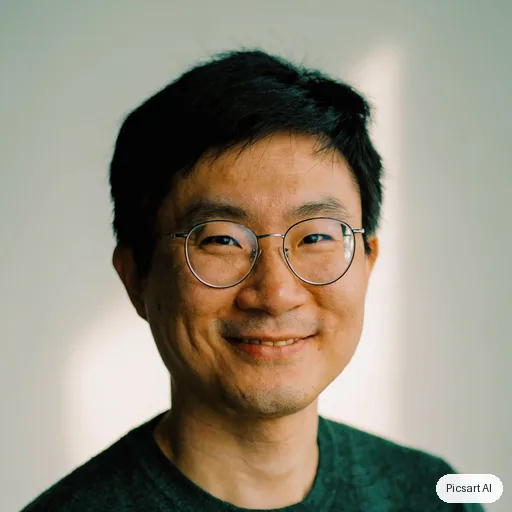 Luma UNI-1: headshot for a startup team page, man in his thirties, East Asian, round glasses, dark green sweater, light background, warm smile